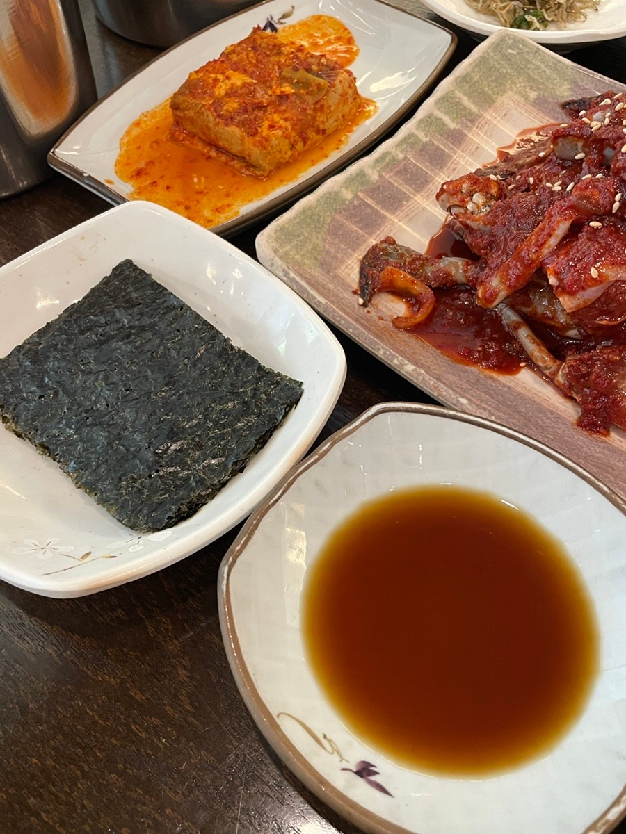食事の場面 - テーブルに並べられたカンジャンケジャン定食を食べている様子